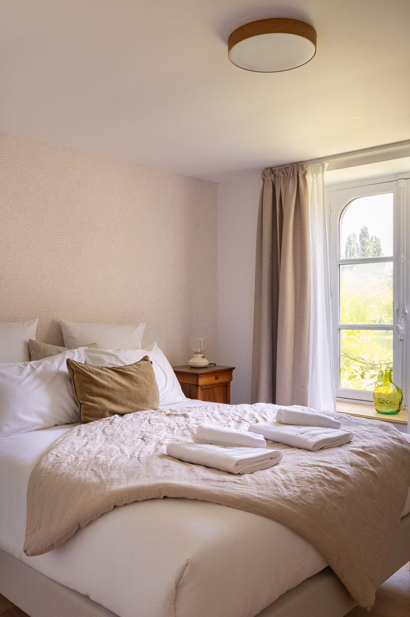 Chambre avec plaid, coussins et fenêtre sur le parc